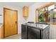 Bright laundry room with wooden cabinets, modern washer/dryer, and a window with a backyard view at 1555 Waterwitch Dr, Orlando, FL 32806