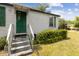 Charming home exterior featuring a green front door with matching shutters, stairs and landscaped yard at 18600 Old Cheney Hwy, Orlando, FL 32820