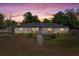 Charming single-story home featuring lush landscaping and a welcoming blue front door under a colorful sunset at 197 Flame Ave, Maitland, FL 32751