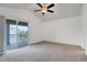 Bright bedroom with a vaulted ceiling, ceiling fan, neutral carpet, and sliding glass doors to a private balcony at 2638 Giardino Loop, Kissimmee, FL 34741