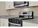 Close up on stainless steel oven with granite countertops and white cabinets above at 30276 Armenia Rd, Leesburg, FL 34748