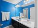 Bright bathroom featuring a double sink vanity, modern lighting, and blue accent walls at 335 Merry Brook Cir, Sanford, FL 32771