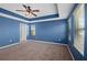 Spacious main bedroom featuring a tray ceiling, ceiling fan, and natural light from two windows at 335 Merry Brook Cir, Sanford, FL 32771