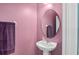 Charming powder room featuring a pedestal sink, oval mirror, and purple accents at 335 Merry Brook Cir, Sanford, FL 32771