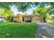 Charming home featuring a lush lawn, palm trees, and a neatly paved driveway leading to the garage at 3509 Battersea Ct, Belle Isle, FL 32812