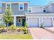Charming townhome featuring a well-maintained lawn, brick driveway, attached garages, and a serene, light gray color palette at 3623 Main Harbor Dr, Kissimmee, FL 34746