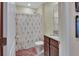 Cozy bathroom features a shower with a floral curtain, vanity with granite countertop, and a soft pink rug at 424 Lazio Cir, Debary, FL 32713