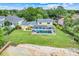 Aerial view of yellow home with a screened-in pool, lush lawn, and waterfront access with a small sandy beach at 5224 Saint Regis Pl, Belle Isle, FL 32812