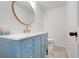 A blue vanity with a marble countertop, gold faucet, and round mirror enhance this stylish half bathroom at 5224 Saint Regis Pl, Belle Isle, FL 32812