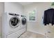 Modern laundry room equipped with side-by-side washer and dryer, tiled floor and shuttered window at 5224 Saint Regis Pl, Belle Isle, FL 32812