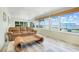 This sunroom includes a wicker coffee table, large windows with water views, and a leather sofa at 5224 Saint Regis Pl, Belle Isle, FL 32812