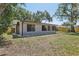 View of the back of a one story home with a large yard, some trees and a partial fence at 525 Legume Dr, Port Orange, FL 32127