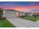 Charming single-story home with a well-maintained lawn, two-car garage, and a welcoming entrance, set against a vivid sunset backdrop at 543 Pine Tree Bridge Trl, St Cloud, FL 34772