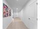 Bright hallway featuring neutral tile flooring, white walls, and decorative art pieces at 543 Pine Tree Bridge Trl, St Cloud, FL 34772