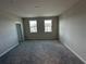 Empty bedroom with carpeted floors, gray walls, two windows, and a white door at 620 Pothos St, Apopka, FL 32703