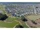 Expansive aerial view of the community, with lush green golf courses, serene ponds, and beautifully landscaped homes, near many amenities at 6328 Merhottein Loop, The Villages, FL 32163
