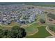 Expansive aerial view of the community, with lush green golf courses, serene ponds, and beautifully landscaped homes, near many amenities at 6328 Merhottein Loop, The Villages, FL 32163