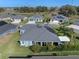 Aerial view featuring a beautiful gray home with solar panels in a lakeside community at 6328 Merhottein Loop, The Villages, FL 32163