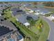 Aerial view of a home with solar panels, a patio, and a lush lawn with colorful landscaping, nestled in a vibrant community at 6328 Merhottein Loop, The Villages, FL 32163
