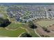 Expansive aerial view of the community, with lush green golf courses, serene ponds, and beautifully landscaped homes, near many amenities at 6328 Merhottein Loop, The Villages, FL 32163