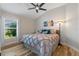 Bright bedroom with a ceiling fan, a comfortable bed, a window with blinds, and wood-look flooring at 6328 Merhottein Loop, The Villages, FL 32163