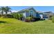 Landscaped side yard showcasing lush greenery, colorful flowering bushes and a decorative home exterior at 6328 Merhottein Loop, The Villages, FL 32163