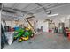 Well-lit garage features a lawn tractor, shelving, and room for two cars or additional storage at 6328 Merhottein Loop, The Villages, FL 32163
