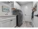 Functional laundry room with modern washer/dryer, sink, white cabinetry, and stylish wood-look flooring at 6328 Merhottein Loop, The Villages, FL 32163