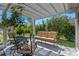 Inviting patio has cushioned furniture set under a trellis and is framed by lush landscaping for quiet outdoor enjoyment at 6328 Merhottein Loop, The Villages, FL 32163