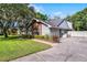 Side view of a house, showing brick details, mature trees, and a well-kept lawn at 687 Saranac Dr, Winter Springs, FL 32708