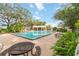 Community pool surrounded by lush greenery, picnic tables, and lounge chairs at 7803 Laurel Oak Ln, Kissimmee, FL 34747