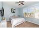 This bedroom has light blue walls, carpet flooring, a ceiling fan, and a large window at 8001 Cool Breeze Dr # 118, Orlando, FL 32819