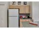 Functional kitchen area with a refrigerator, light wood cabinets, and coffee station, offering practicality at 8471 Secret Key Cv, Kissimmee, FL 34747