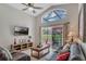 Bright living room with a ceiling fan, tv, leather couches, and sliding door to a screened in pool area at 8471 Secret Key Cv, Kissimmee, FL 34747