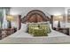Luxurious primary bedroom with an ornate headboard, decorative pillows, and stylish nightstands with lamps at 8471 Secret Key Cv, Kissimmee, FL 34747