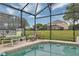 Screened-in pool area with chairs and tables for lounging outdoors, with a view of the grassy backyard at 8471 Secret Key Cv, Kissimmee, FL 34747