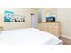 Cozy bedroom showcasing a queen bed, dresser with television, and bright artwork at 9004 Majesty Palm Rd, Kissimmee, FL 34747