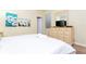 Cozy bedroom showcasing a queen bed, dresser with television, and bright artwork at 9004 Majesty Palm Rd, Kissimmee, FL 34747