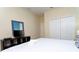 A well-lit bedroom is equipped with a cozy queen-sized bed and an entertainment center with a sleek, modern TV at 9004 Majesty Palm Rd, Kissimmee, FL 34747