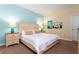 Bright bedroom featuring a queen bed, soft beige carpet, and colorful floral wall art at 9004 Majesty Palm Rd, Kissimmee, FL 34747
