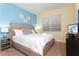 A brightly lit bedroom features a cozy king-sized bed with fresh white linens and stylish blue accent pillows at 9004 Majesty Palm Rd, Kissimmee, FL 34747