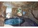 Hot tub beneath a rock overhang featuring a brick pathway and steps toward the pool at 9004 Majesty Palm Rd, Kissimmee, FL 34747