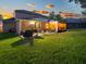 Beautiful backyard featuring green grass, a patio, and a screened-in lanai at sunset at 925 Counts Crest Cir, Apopka, FL 32712