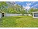 Large, grassy backyard with a white fence, bordered by mature trees, offering ample outdoor space at 976 W Gaucho Cir, Deltona, FL 32725