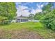 Lush backyard with green grass, a white privacy fence, mature trees, and an enclosed porch on house at 976 W Gaucho Cir, Deltona, FL 32725