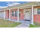 Inviting front porch with brick columns, a storm door, and cheerful seasonal decor at 976 W Gaucho Cir, Deltona, FL 32725