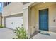 Close up of the blue front door and two-car garage with a concrete driveway at 1068 Brooklet Dr, Davenport, FL 33837