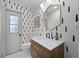 Modern bathroom with patterned wallpaper, stylish mirror and wood-look vanity at 107 Coveridge Ln, Longwood, FL 32779