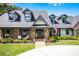 Charming front exterior with brick facade, dormer windows, covered porch, and landscaped garden at 107 Coveridge Ln, Longwood, FL 32779