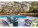 Outdoor pool with comfortable seating and a screened-in enclosure surrounded by mature trees at 120 W Trade Winds Rd, Winter Springs, FL 32708